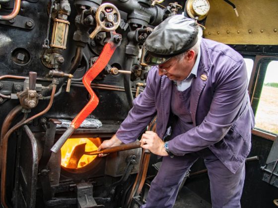 A fireman shovels coal into a loco firebox